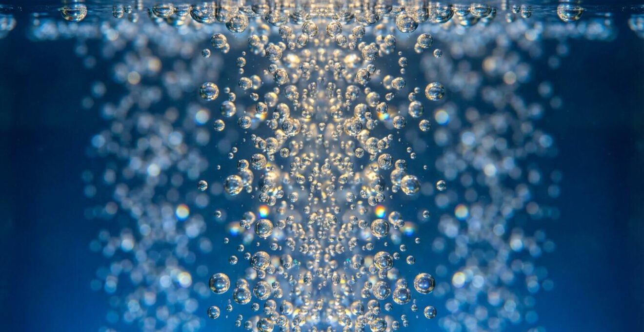 Close-up underwater view showing fine champagne bubbles from air blowers creating shimmering patterns in spa water
