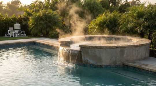 Elevated spa with cascading water feature flowing into a crystal-clear swimming pool, showcasing dual temperature control system