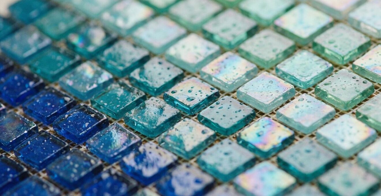 Gradient pattern of blue to turquoise glass mosaic tiles arranged on installation grid
