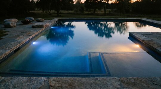 Evening pool illuminated with calming blue and warm amber underwater lights creating a serene atmosphere for stress relief