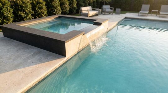 Raised corner spillover spa with glass-like water sheet cascading into modern rectangular pool
